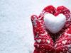 Red mittens holding a snowball shaped as a heart