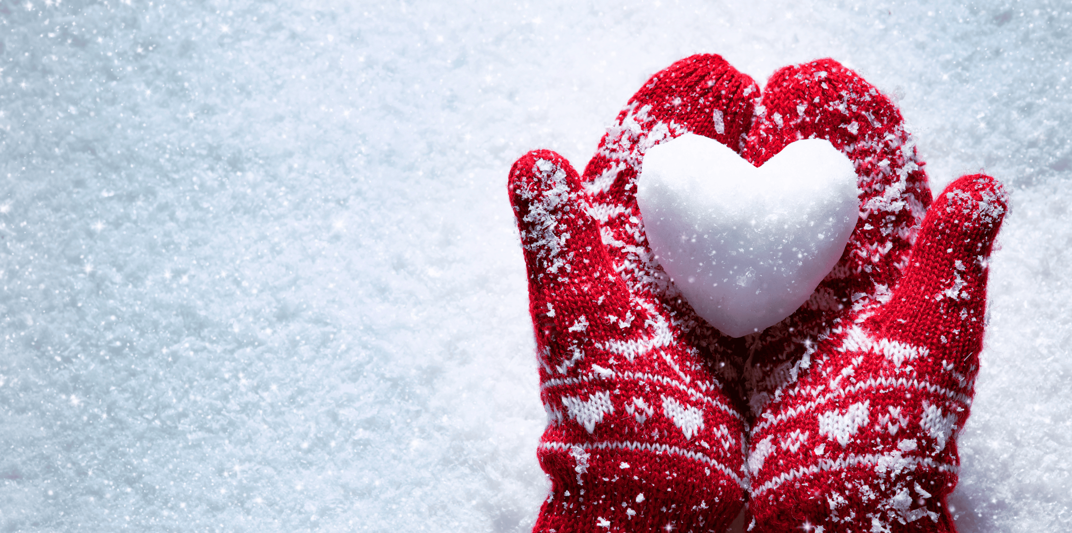 Red mittens holding a snowball shaped as a heart