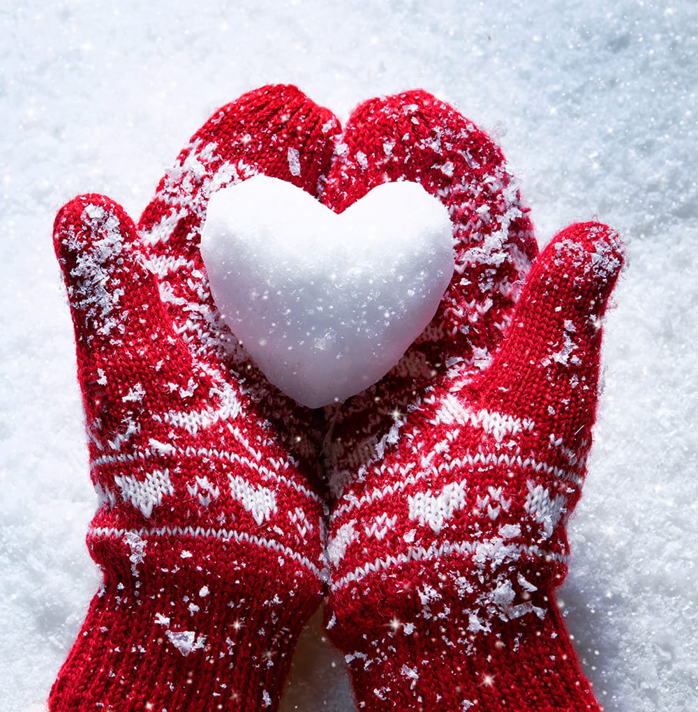 Red mittens holding a snowball shaped as a heart