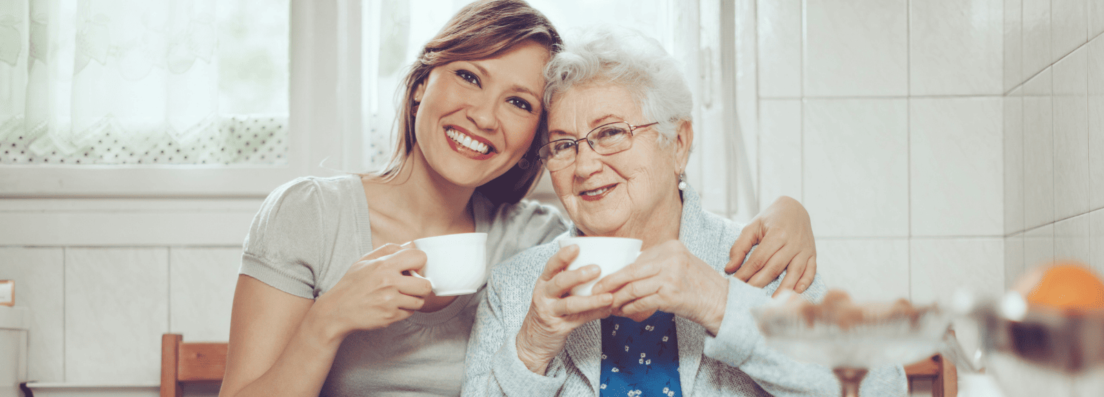 Une femme et une aînée sourient, une tasse de thé à la main